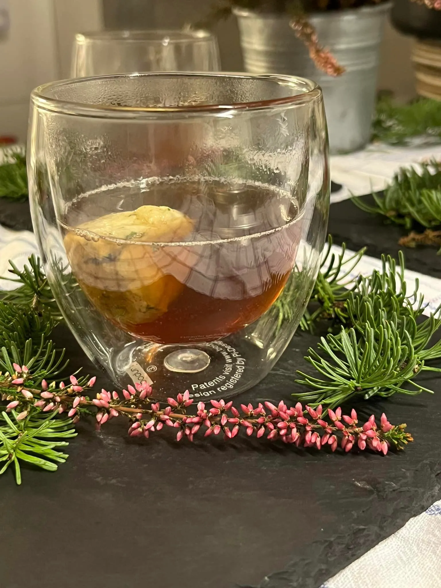 Festland – Restaurant & Vinothek – Eine Tasse Tee, möglicherweise ein immunstärkender Aufguss, serviert in einem doppelwandigen Glas. Festland - Restaurant & Vinothek -